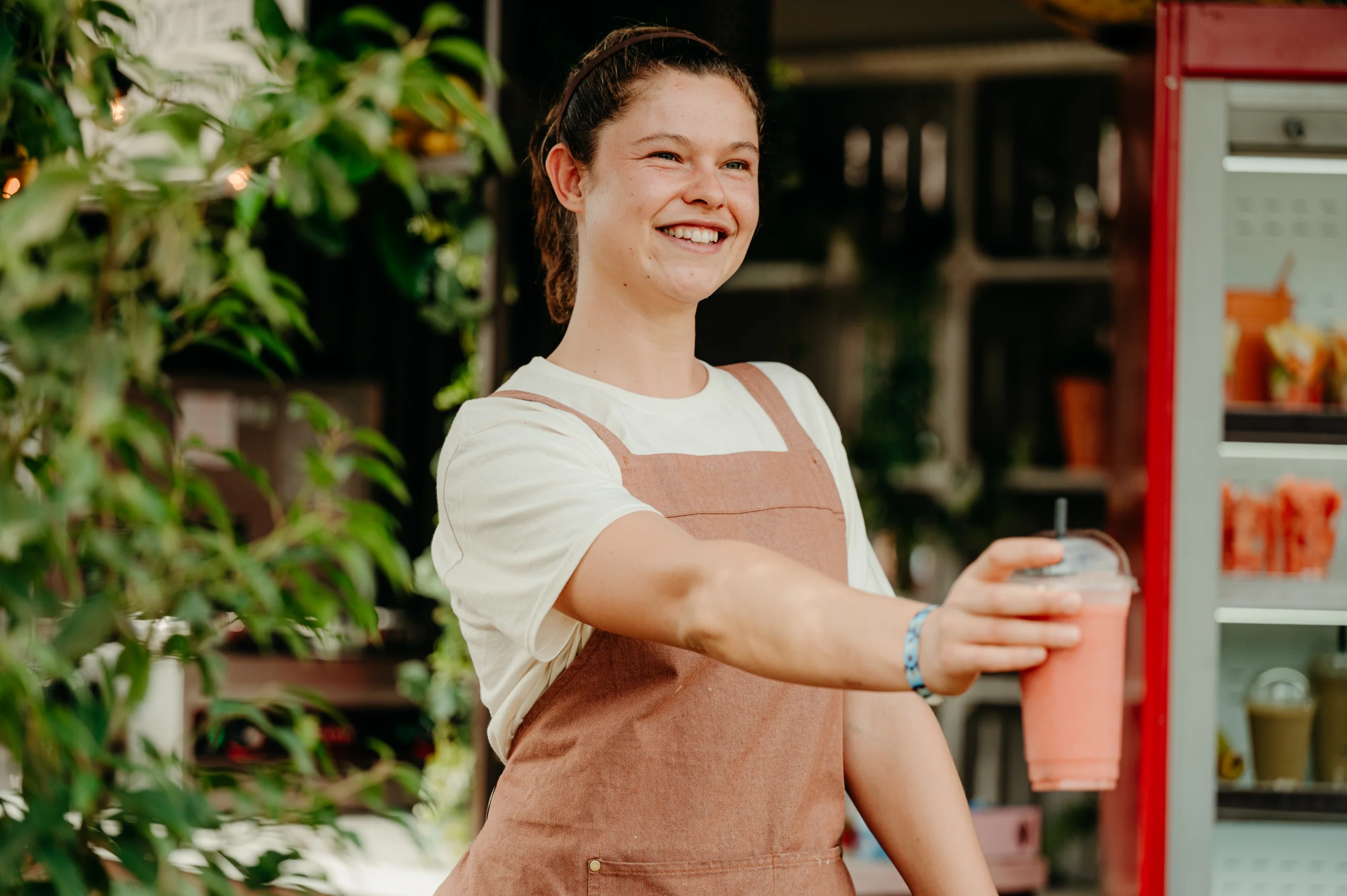 Medewerker overhandigt een verse smoothie aan een gast