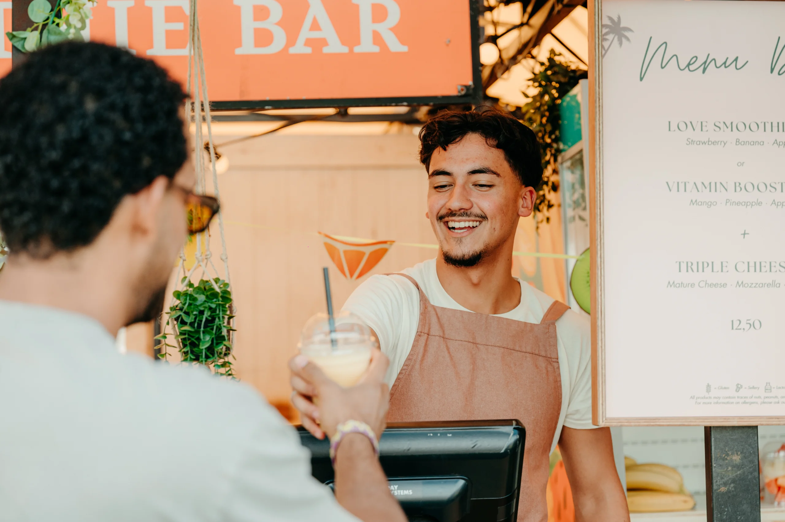 Medewerker overhandigt een verse smoothie aan een gast